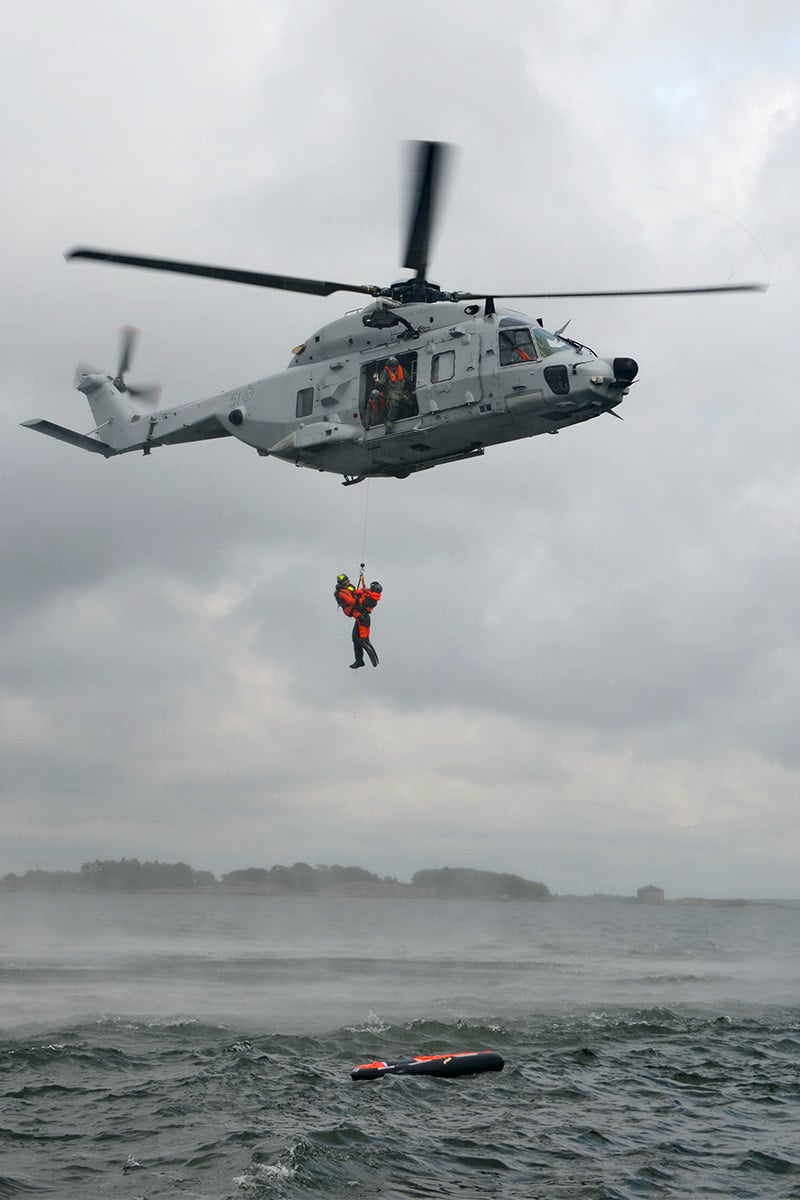 Helicopter rescue operation with a person being winched hanging below the helicopter